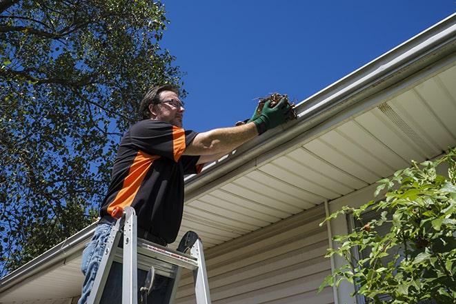 a worker fixing a broken gutter on a residential home in Farmingdale